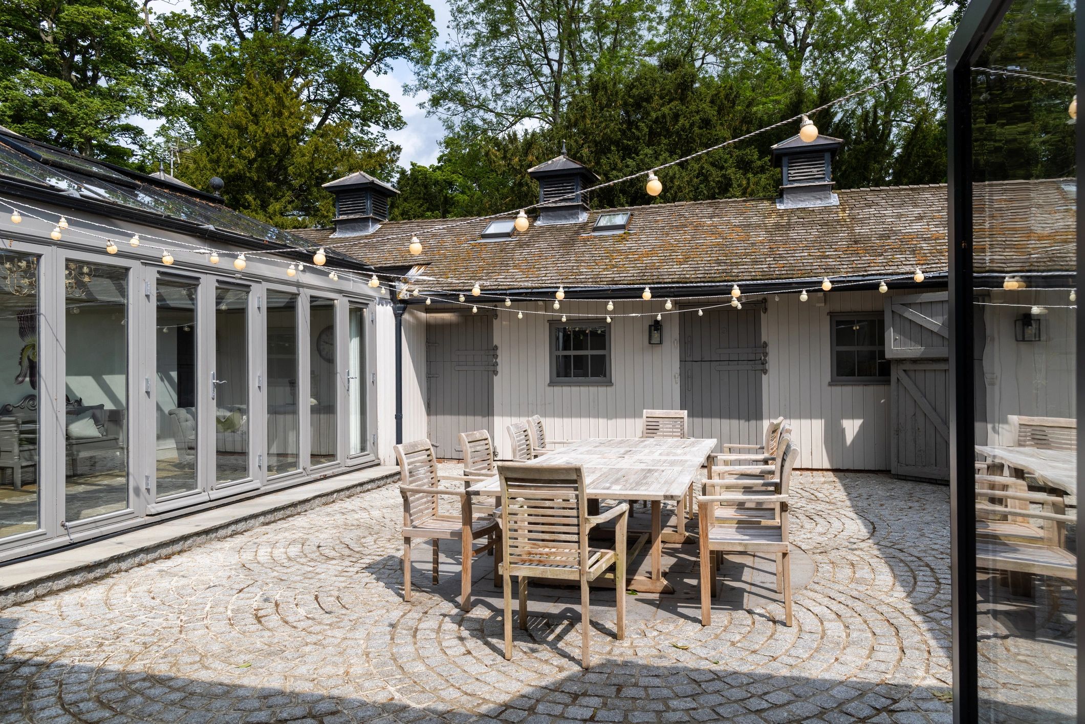 Outdoor courtyard with long wooden table under string lights